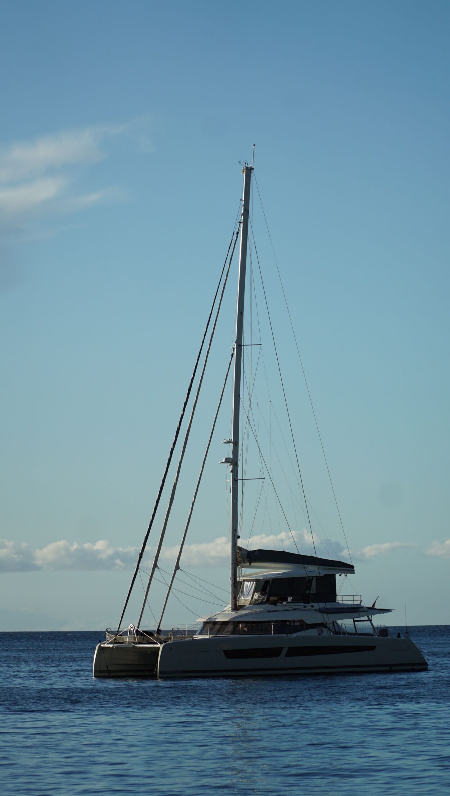 Catamarán fondeado con el mástil recortado contra el cielo